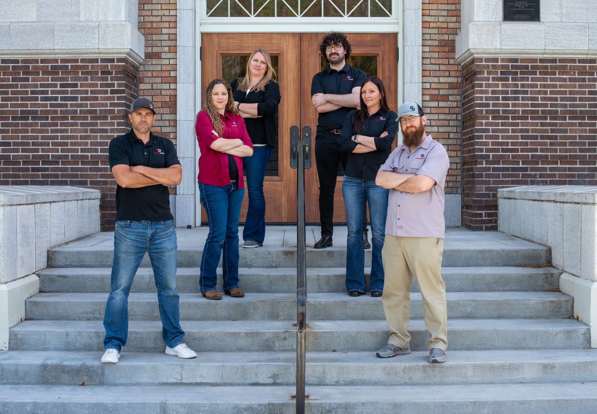 Group standing on steps outside a brick building.