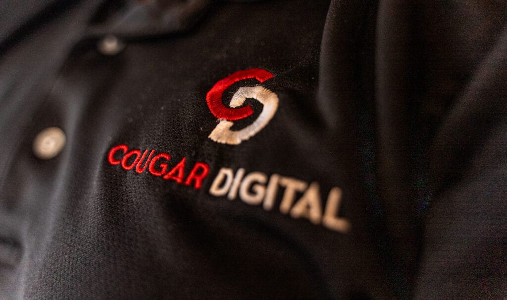Black shirt with Cougar Digital logo embroidery.