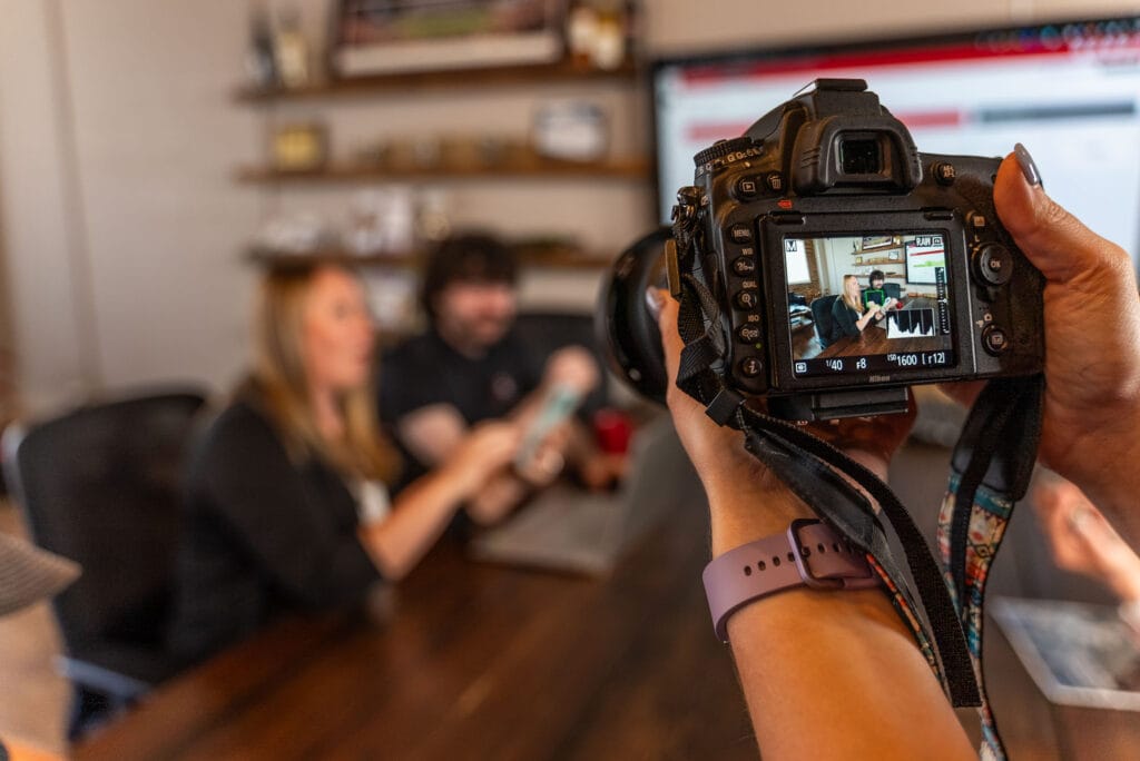 Camera captures people working at a table meeting.