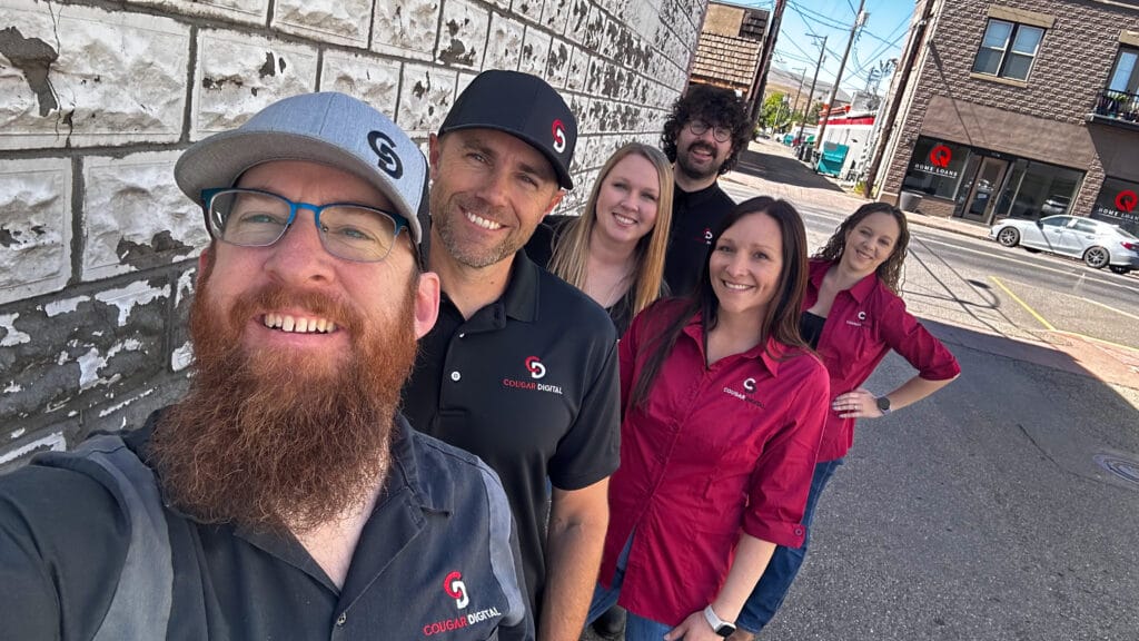Smiling team in branded shirts on street.