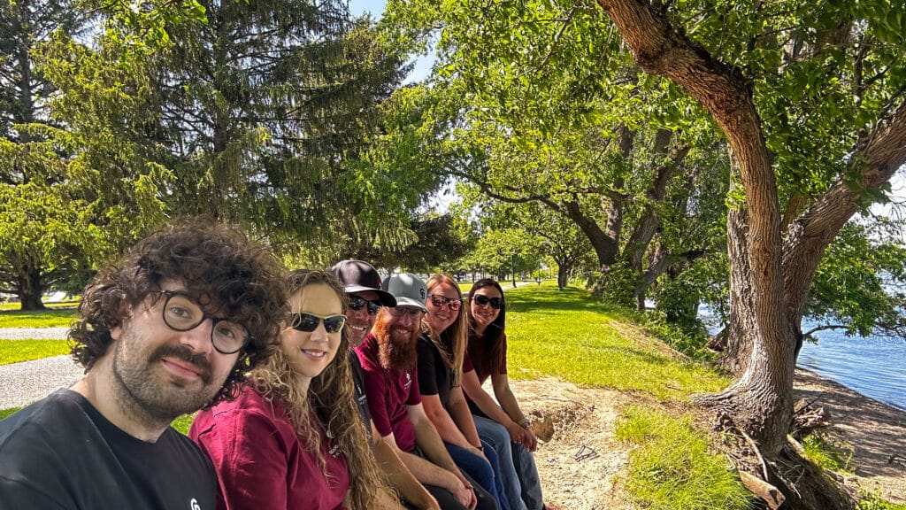 Group sitting under trees by the lake