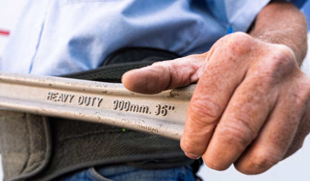 Person holding heavy-duty wrench, close-up view.
