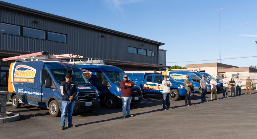 Team standing with Silverline service vans outside building.