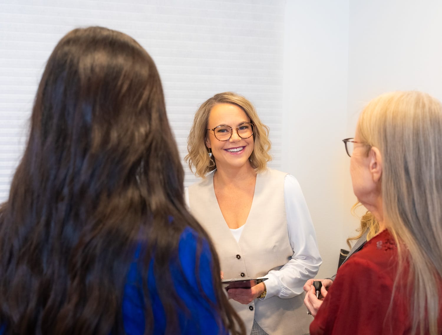 Smiling woman talking with two others indoors.