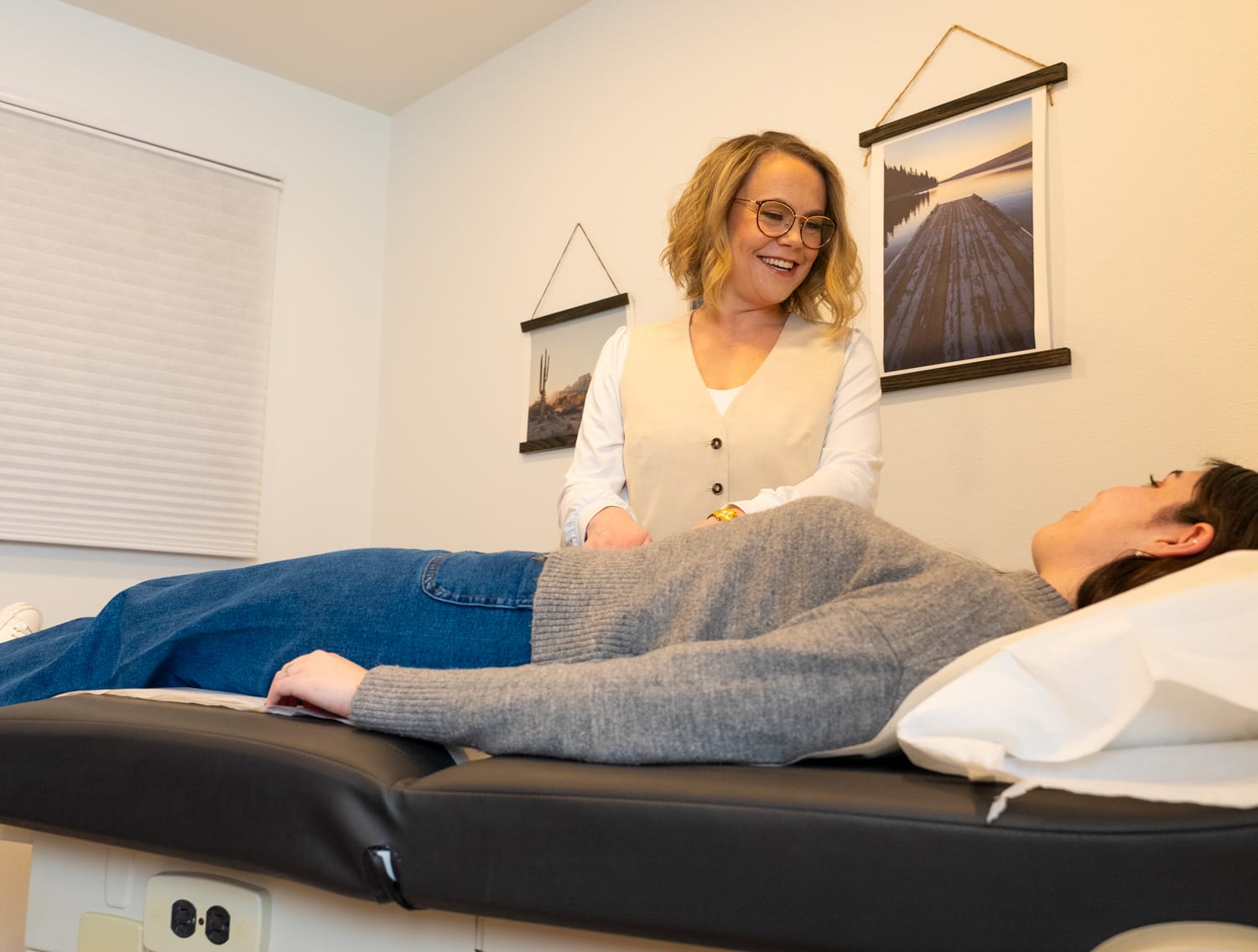 Healthcare professional smiling at patient on exam table.
