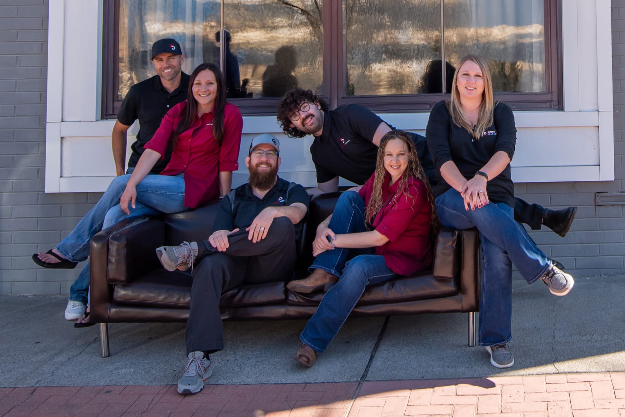 Group sitting on outdoor couch, smiling together.