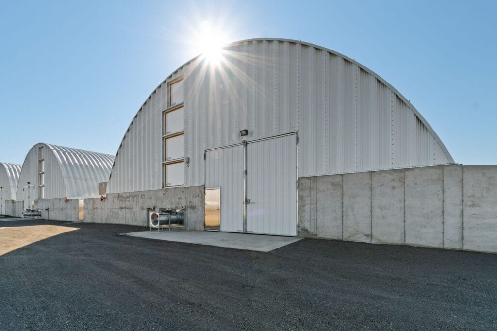 Quonset hut buildings with concrete walls under sunflare.