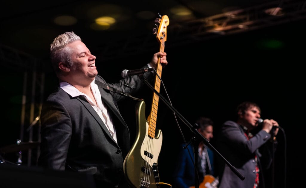 Smiling musician with bass guitar performing on stage.