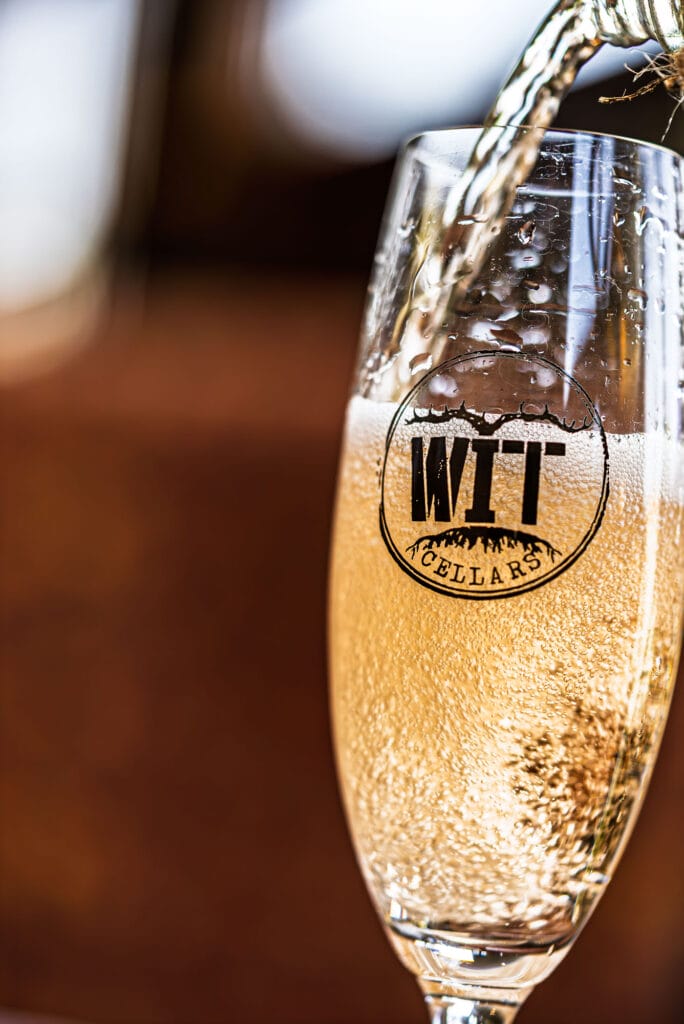 Pouring sparkling wine into glass with logo.