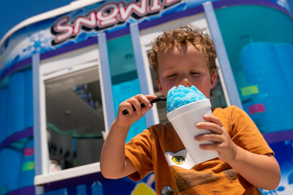 Child enjoying blue snow cone on sunny day