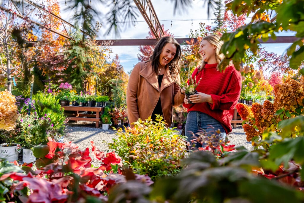 Two women enjoying plants in a nursery garden.