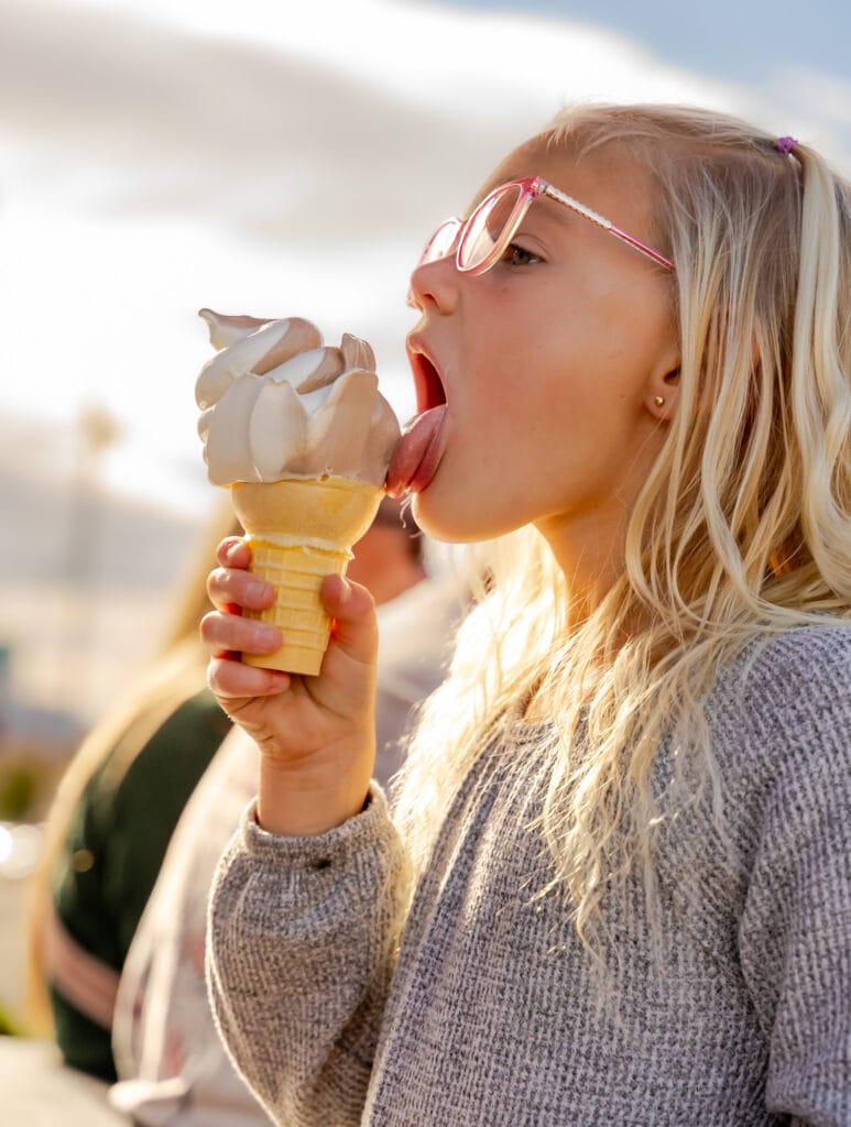 Child enjoying soft serve ice cream outdoors.