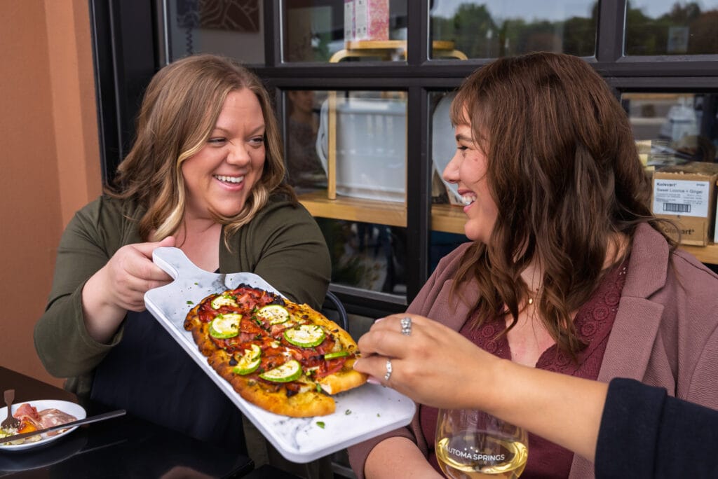 Friends enjoying pizza and wine outdoors.