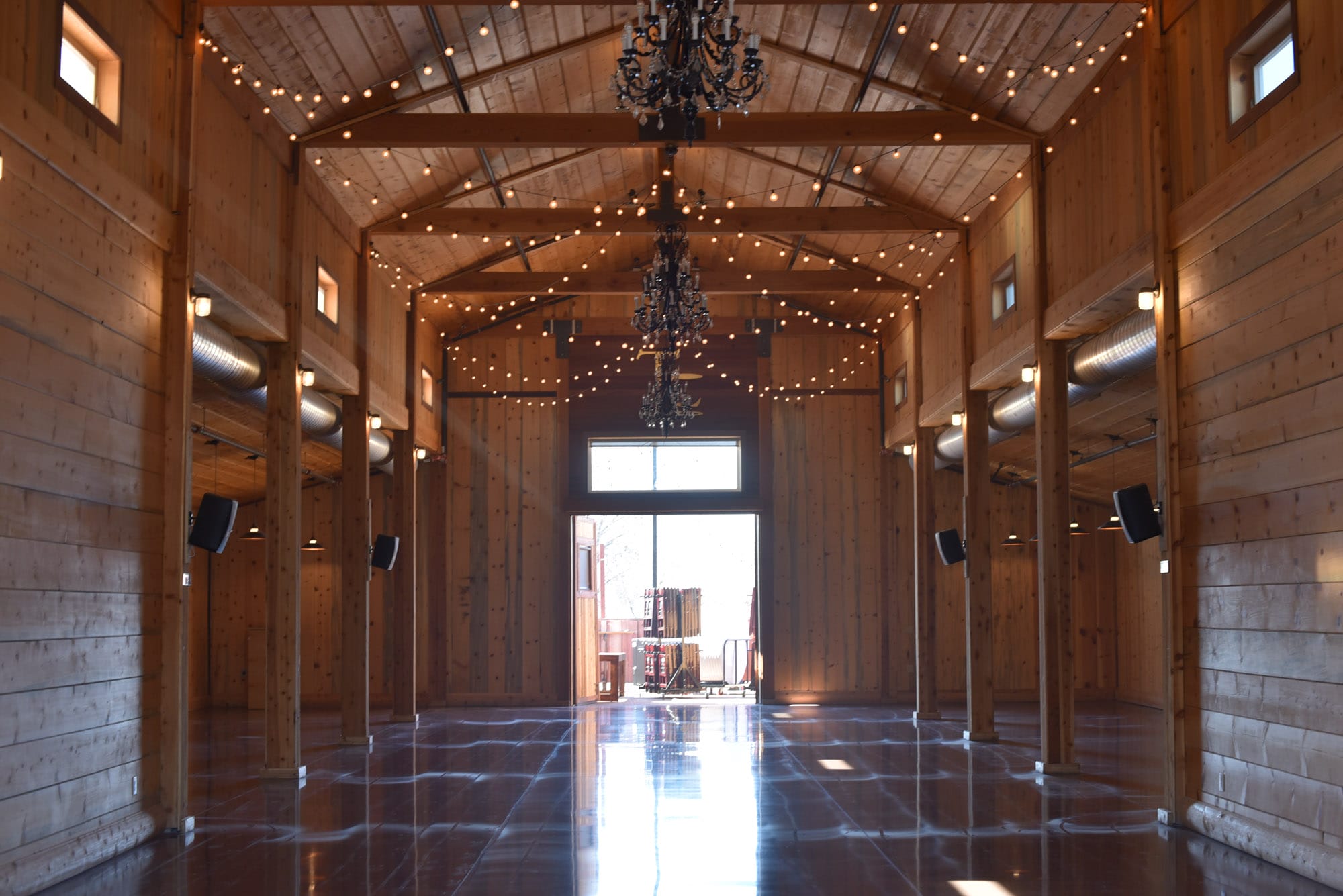 Spacious rustic barn interior with chandeliers and lights.