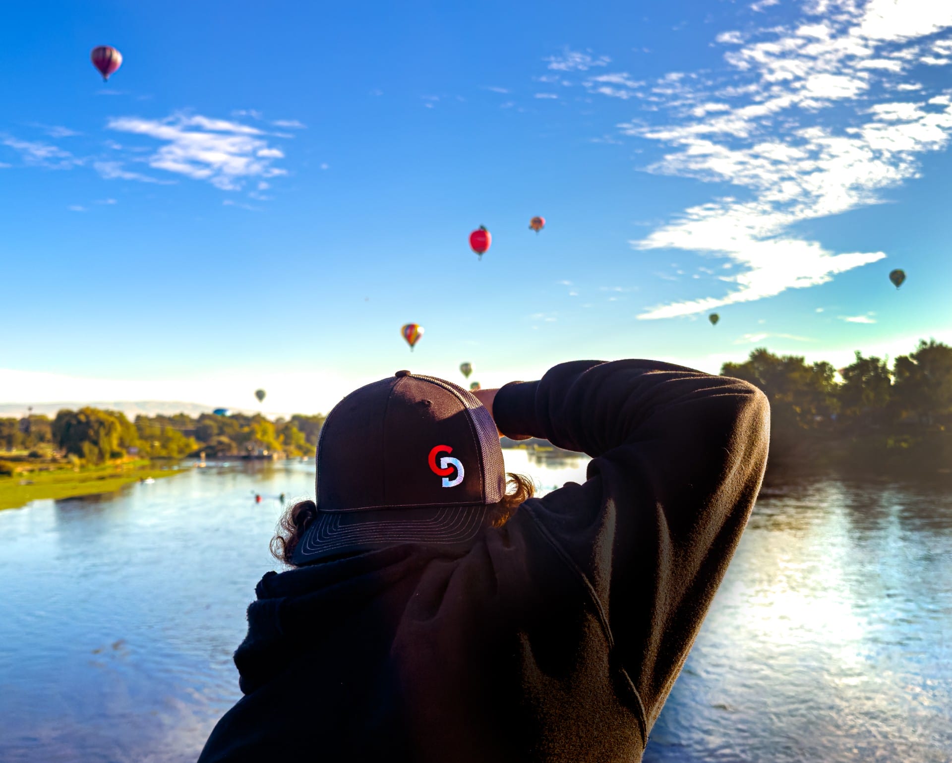 Photographer capturing hot air balloons over a river.
