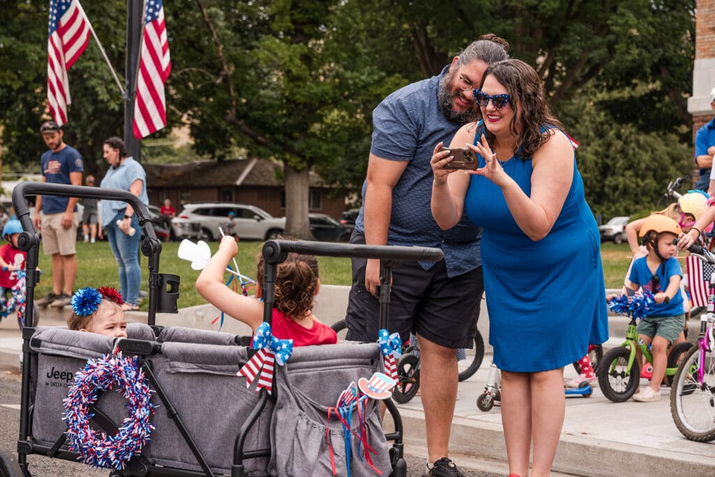 Family celebrating at a patriotic parade with stroller.