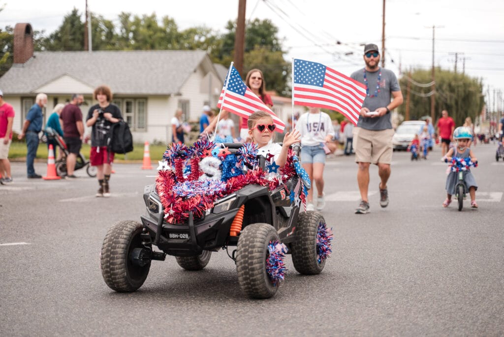 Child rides decorated car in festive parade.
