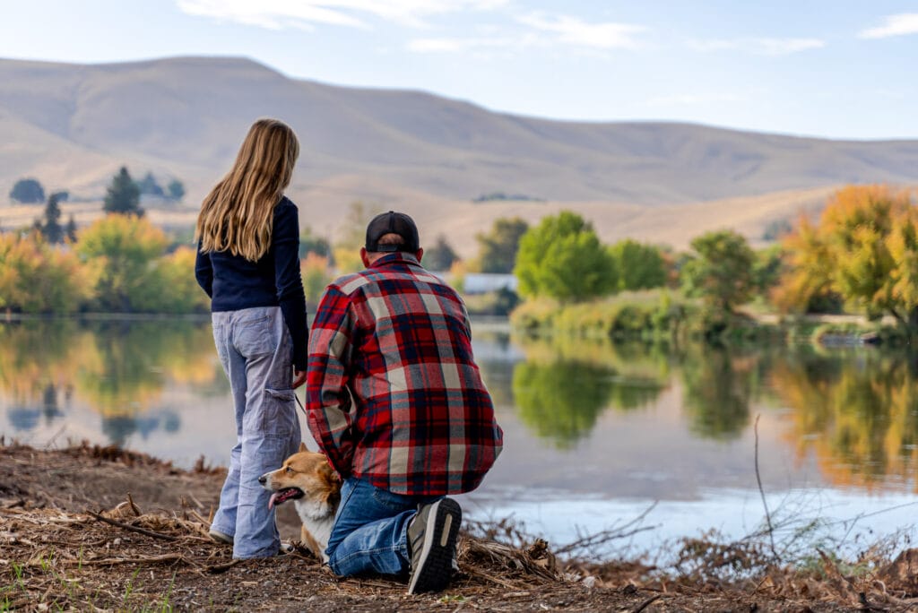 People and dog enjoying lake view in autumn