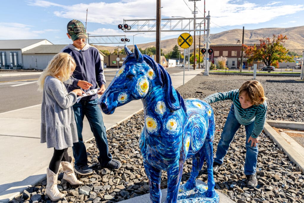 Children interacting with Van Gogh starry night horse sculpture.
