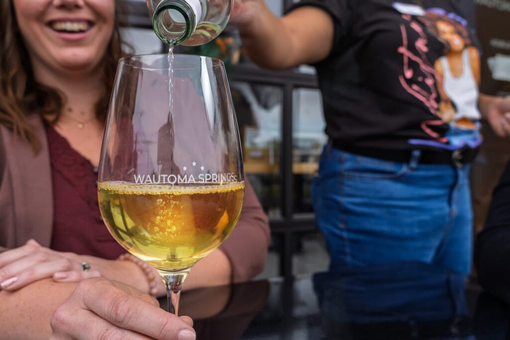 Pouring white wine into glass at Wautoma Springs.
