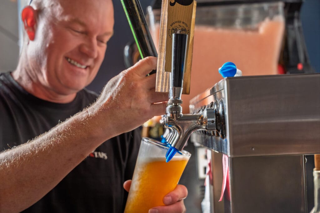 Man pouring draft beer from tap.