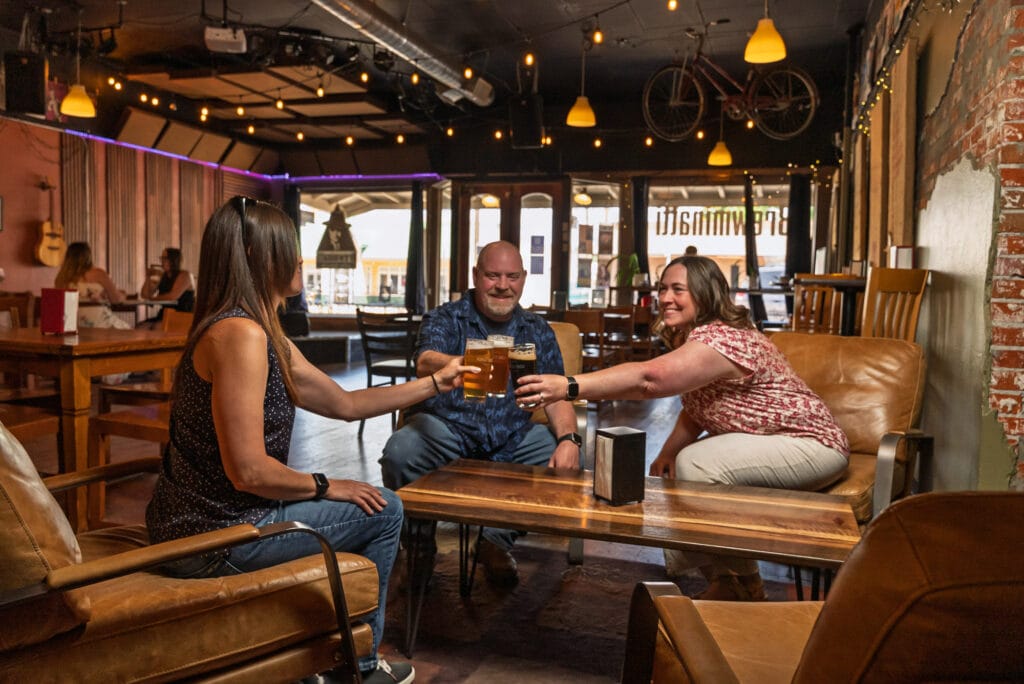 Three people toasting with beers in a pub.