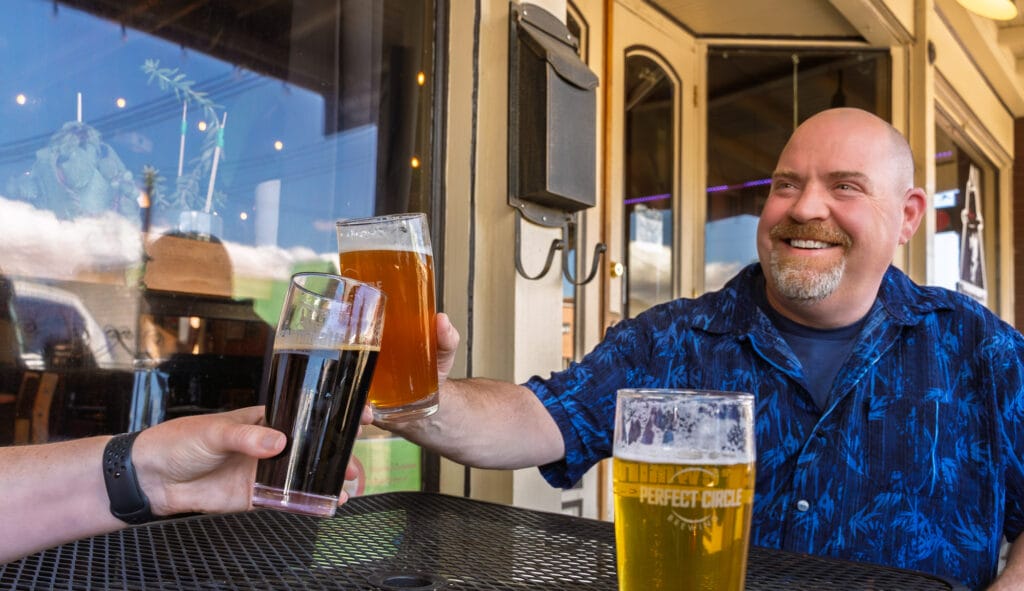 People toasting with beers at an outdoor cafe.