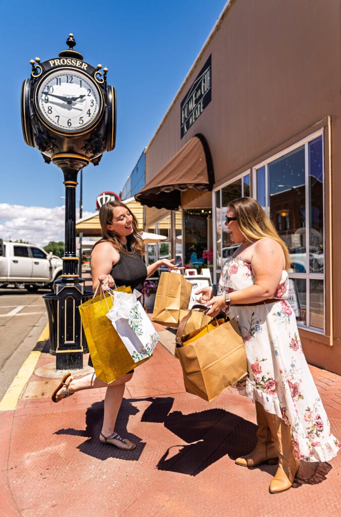 Women shopping outside under a clock in Prosser.