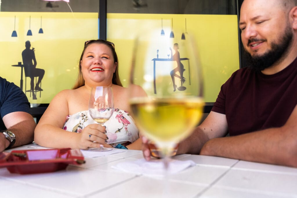 Smiling friends enjoying wine at outdoor cafe.