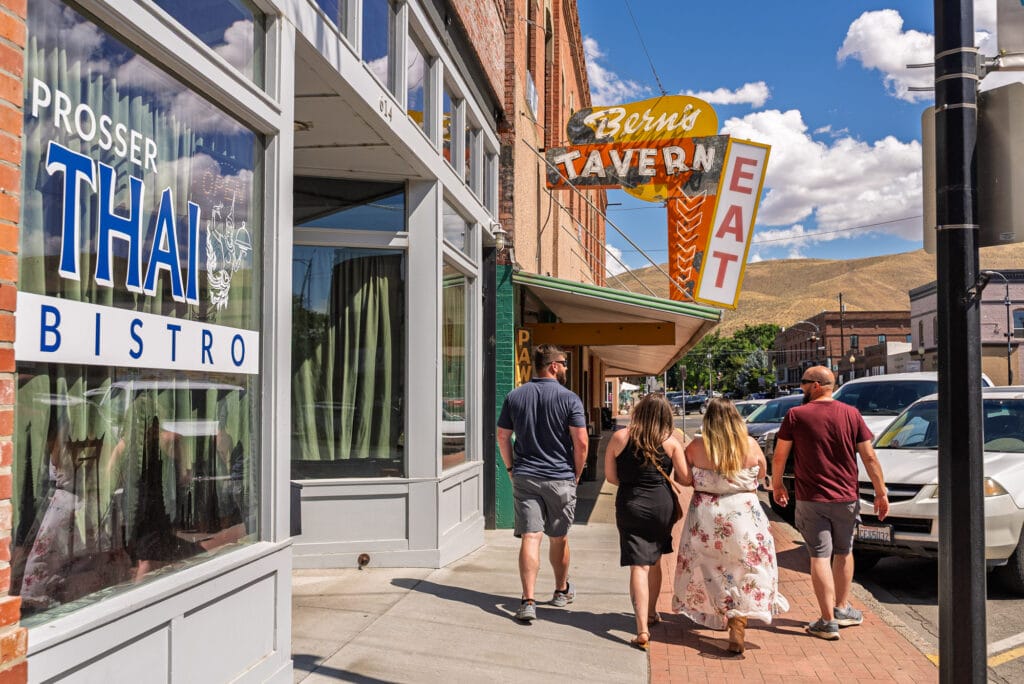 People walking near restaurants in a small town.