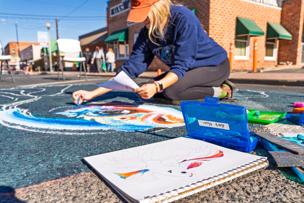 Artist creating colorful chalk street art.