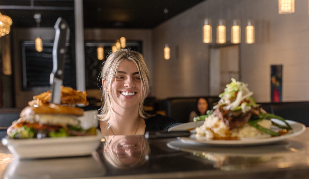 Smiling woman admiring gourmet food on plates