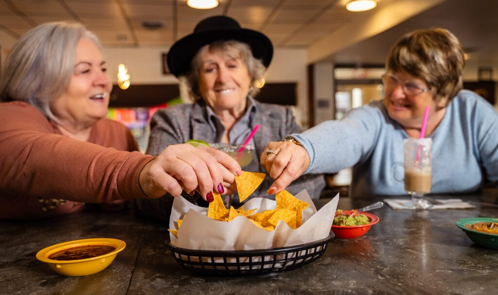 Friends enjoying chips and drinks at a table.