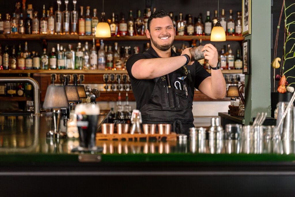 Bartender smiling while shaking cocktail shaker.