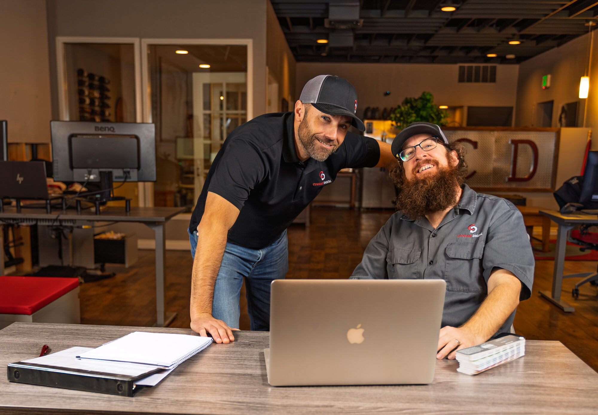 Two men smiling in office with laptop