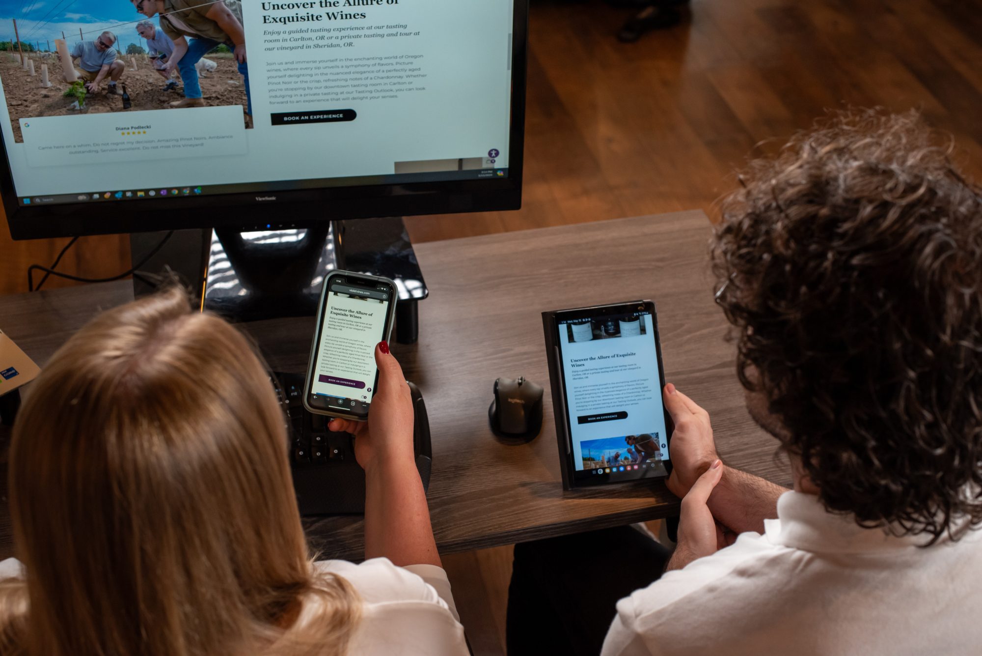 Two people reviewing a winery website on multiple devices