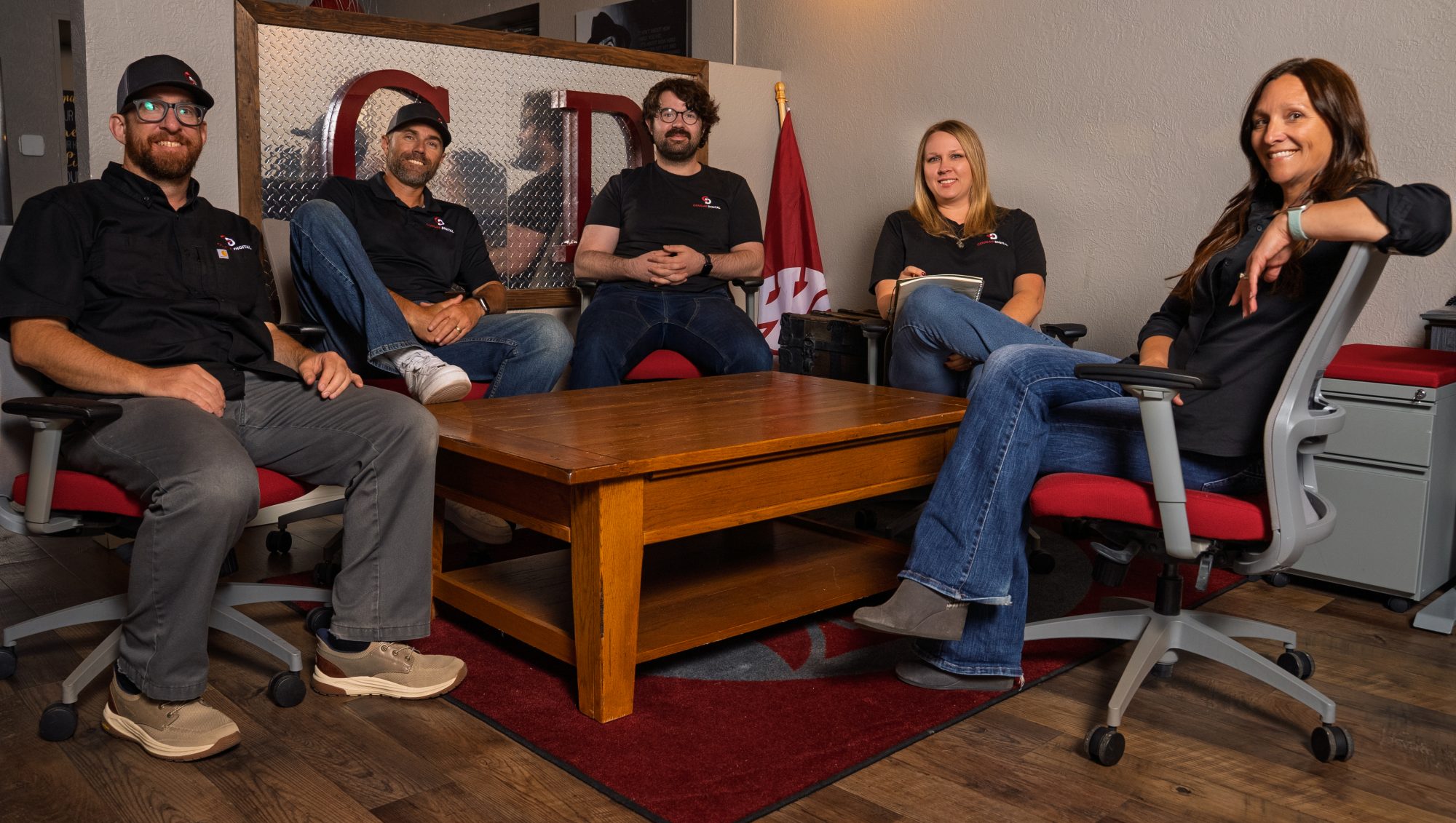 Five team members in matching black shirts posing in office