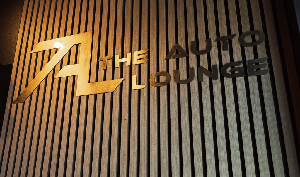 The Auto Lounge gold logo on slatted wood wall