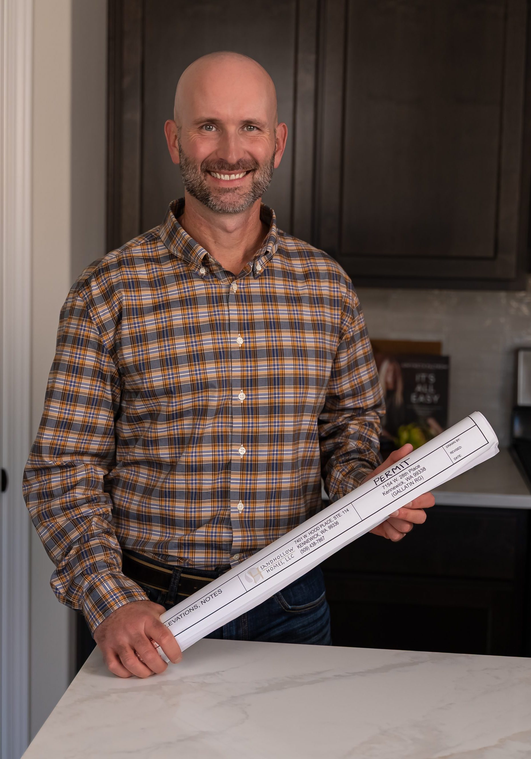 Smiling man holding rolled home building permit documents
